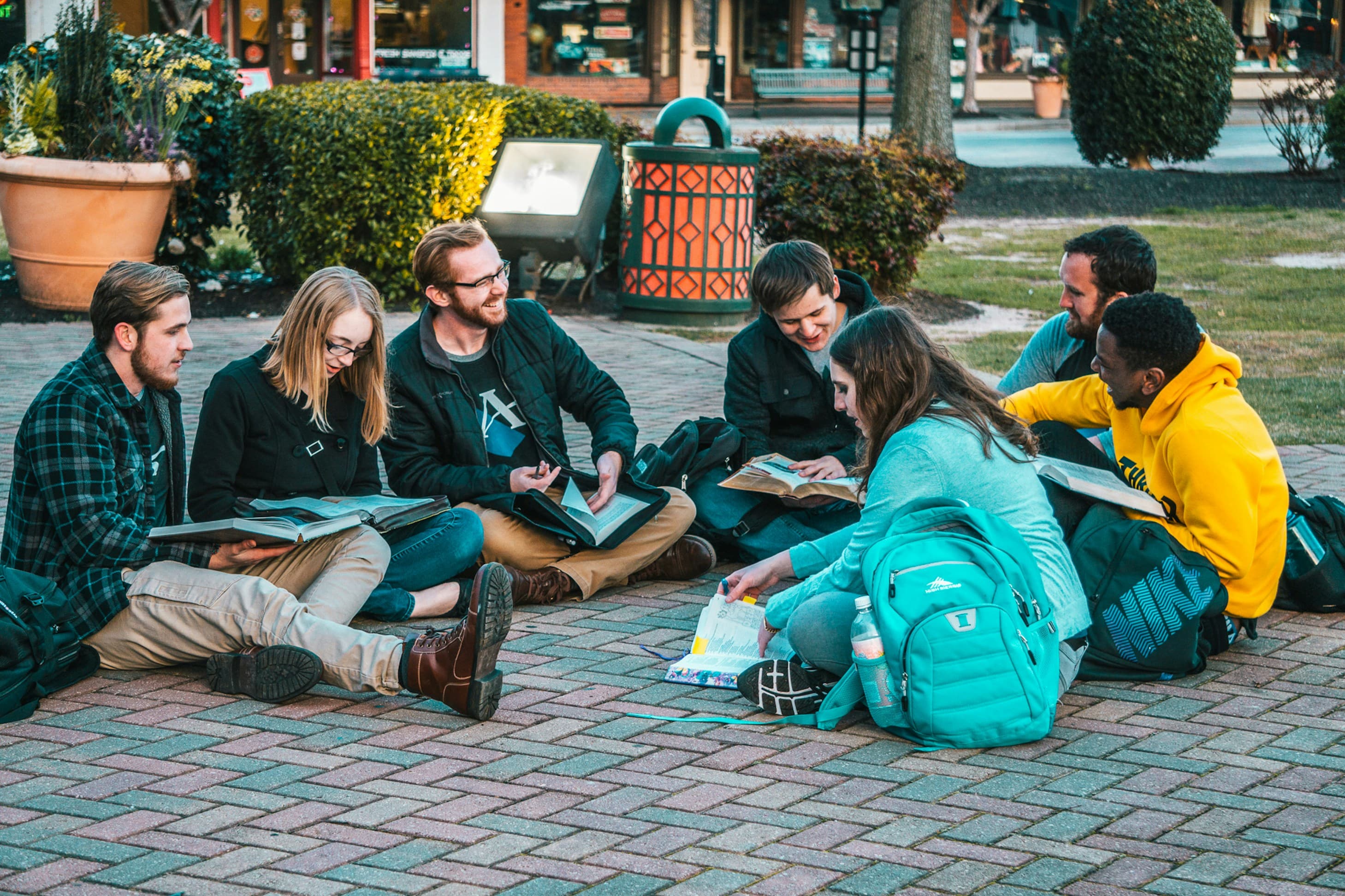 Students sitting together with books on a campus walkway