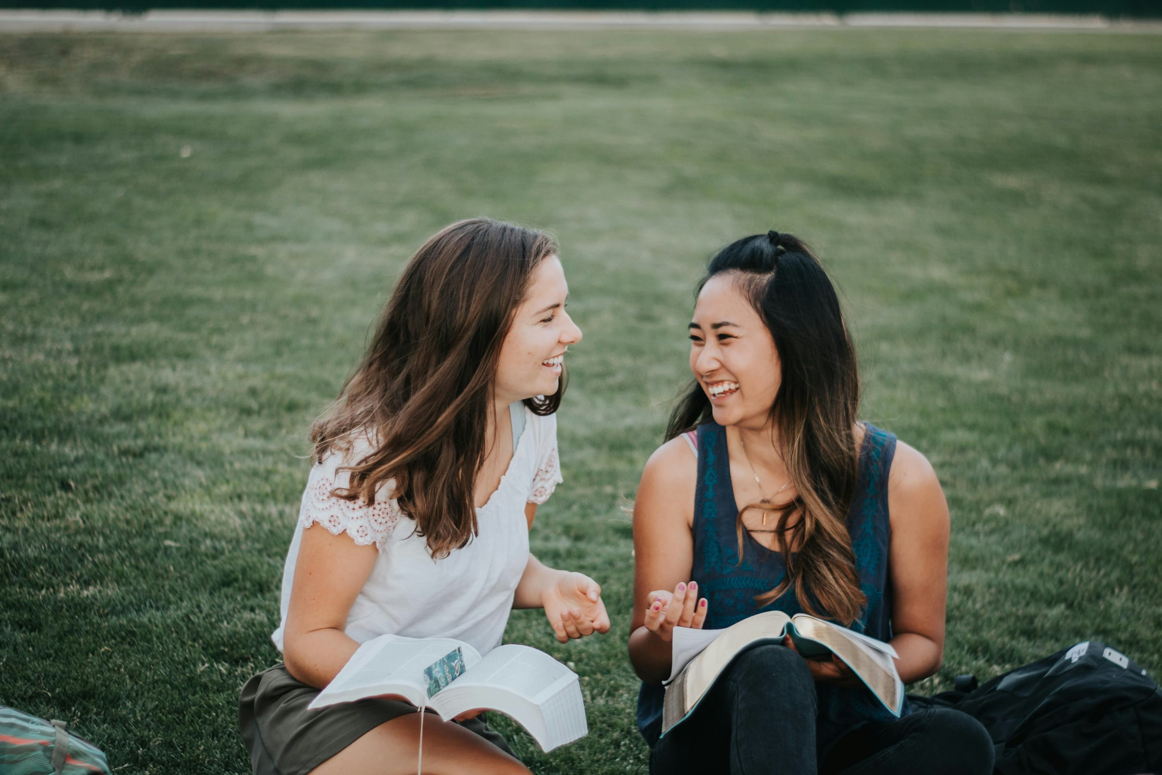 Two students sharing a conversation and notebooks outdoors