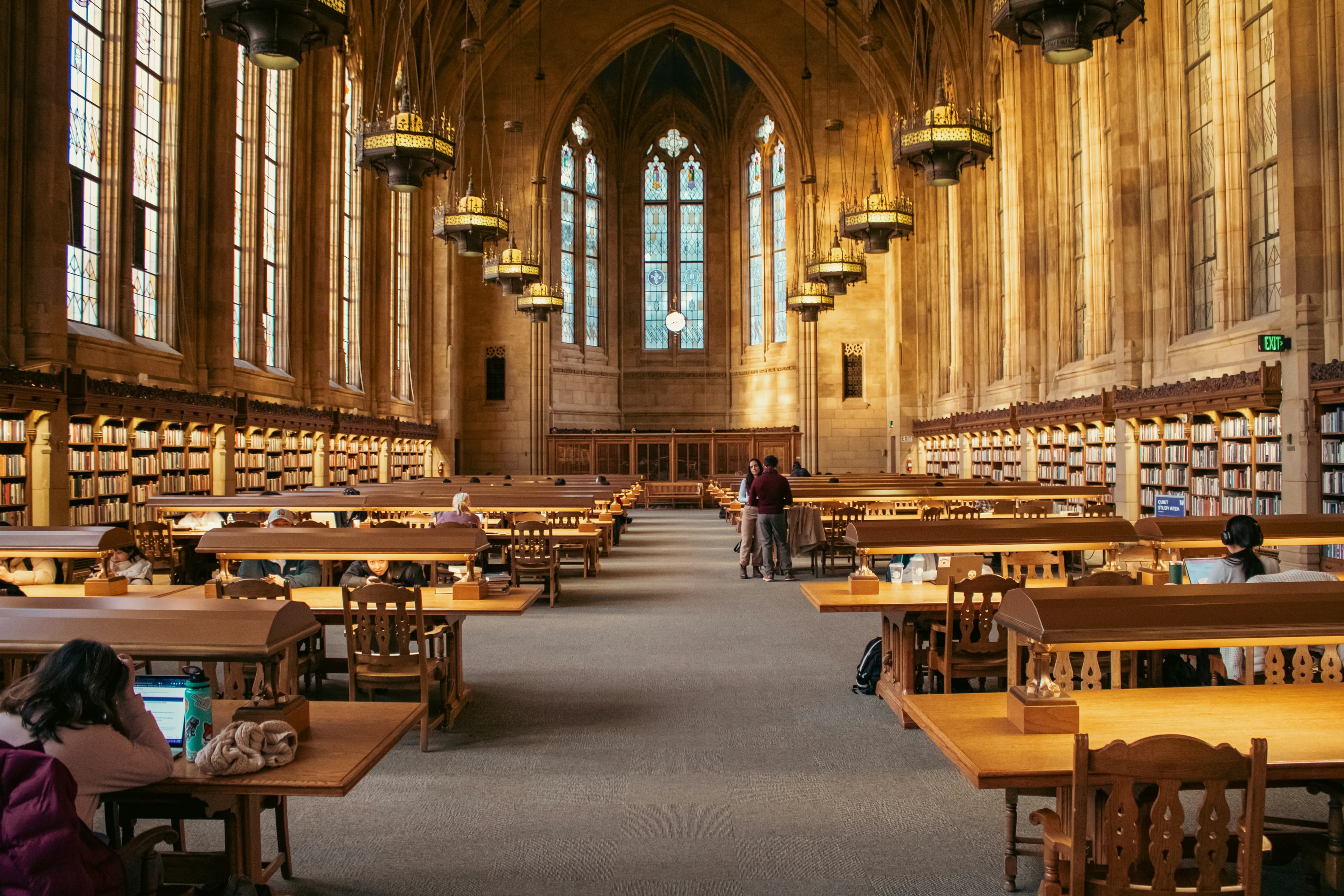 A quiet university library with students at study tables